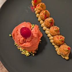 Exquisito postre de pistacho y frambuesa con mutzen crujientes y sorbete cremoso