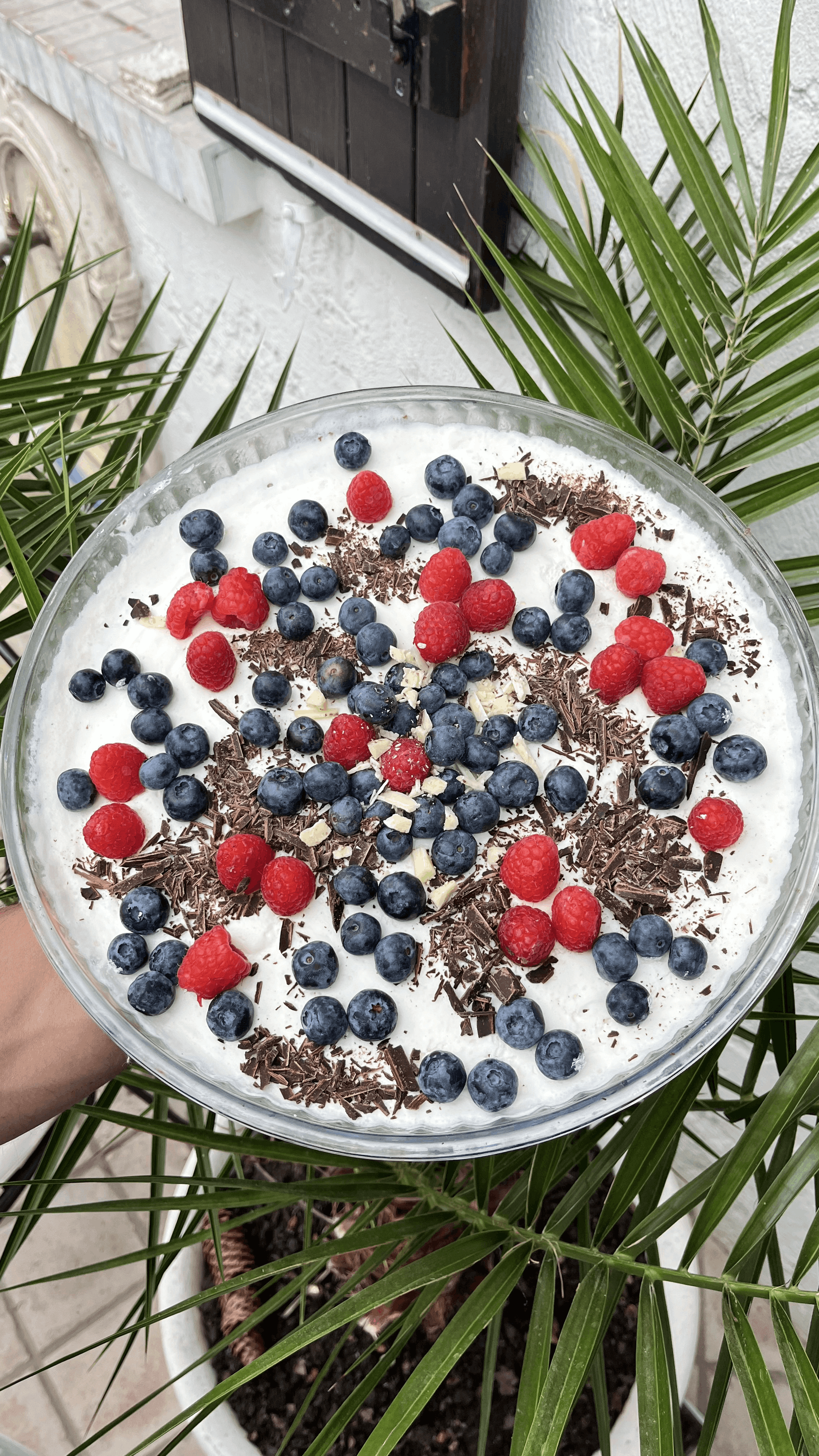 Présenté dans son écrin de verre, ce dessert est une véritable ode à la légèreté. Sur une base aérienne, une mousse de crème fouettée onctueuse accueille un jardin de myrtilles sauvages et de framboises acidulées. Le tout est parsemé de fins copeaux de chocolat noir et blanc, créant un contraste parfait entre le fondant de la crème et le peps des fruits rouges.