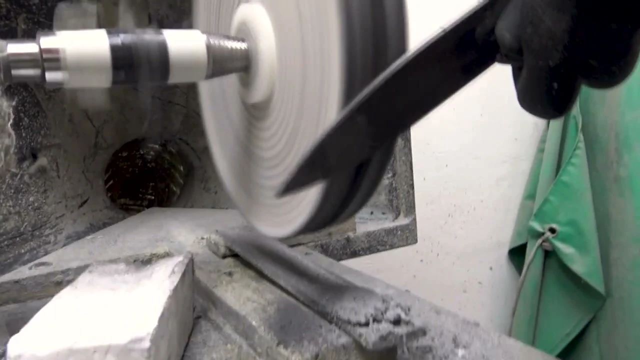 Tight side-on of a blade pressed against a spinning buffing wheel