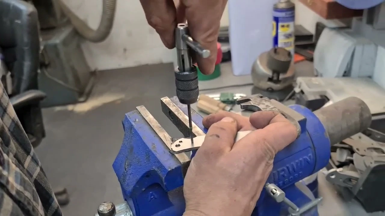 Drill press boring a handle component held in a vise