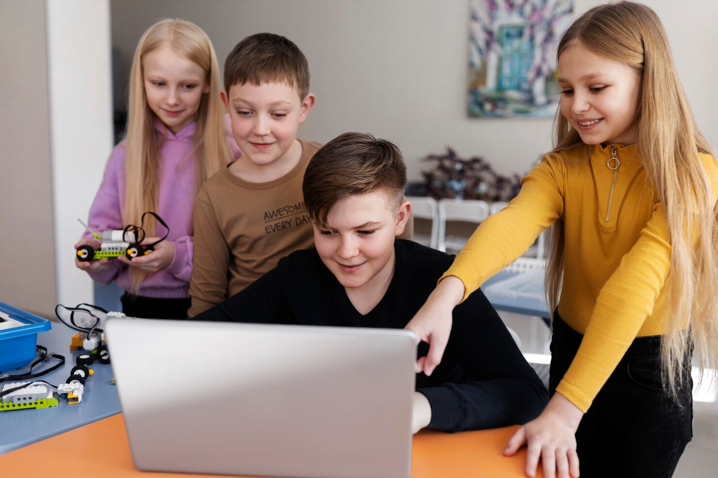 Group of young students collaborating on a robotics project while using a laptop, fostering teamwork and technical skill development.