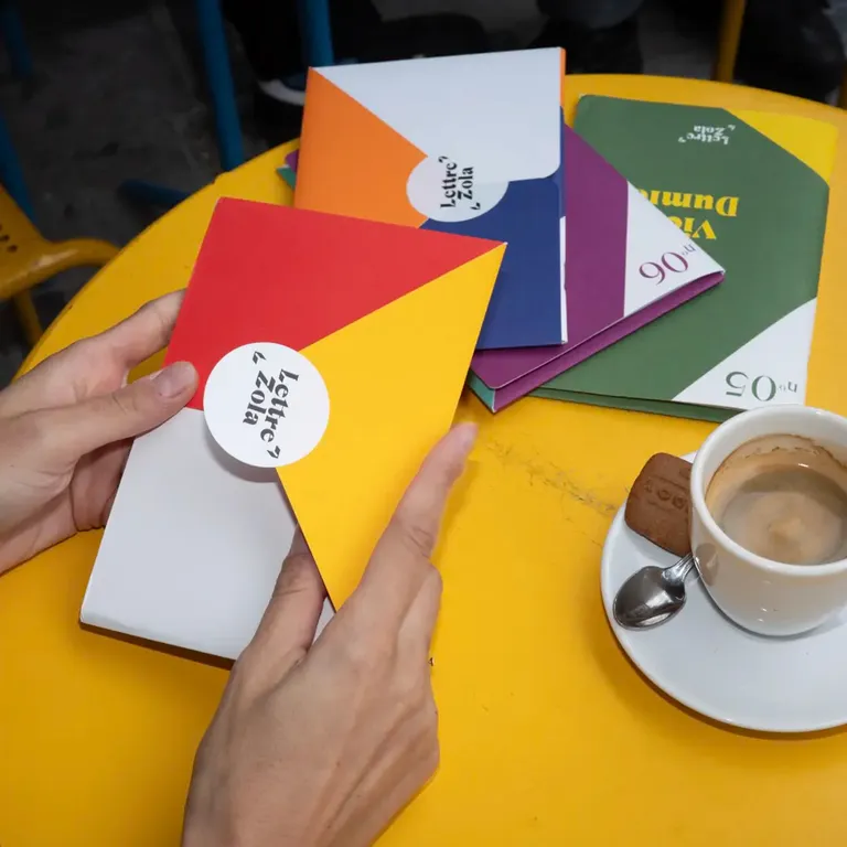 Un lecteur en train de déplier les lettres zola reçues dans sa boîte aux lettre