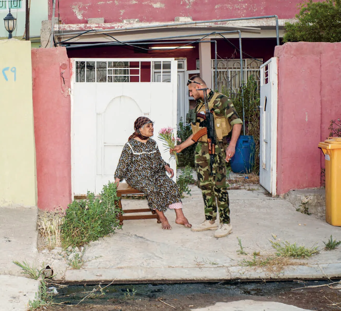 Un soldat tend un bouquet de fleur à une vieille personne
