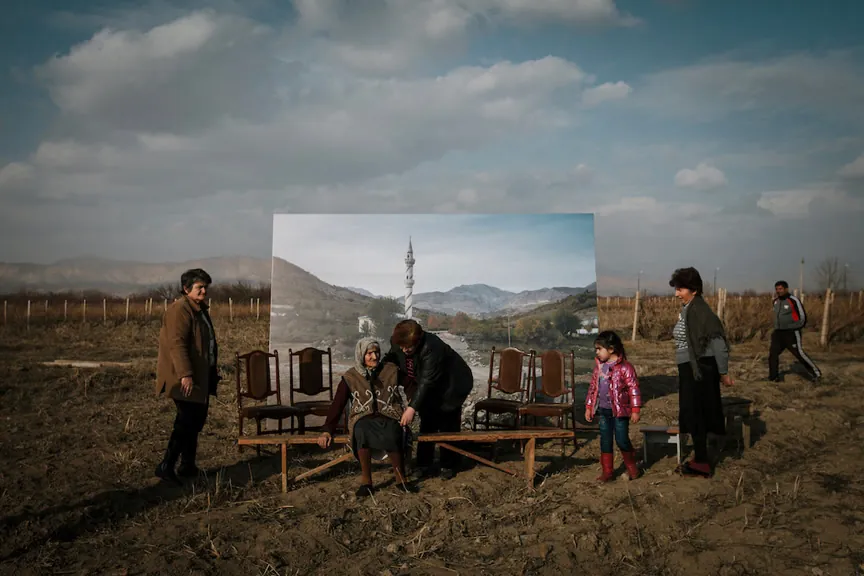 Une famille se trouve devant une vieille photo géante du paysage dans lequel elle se tient. 