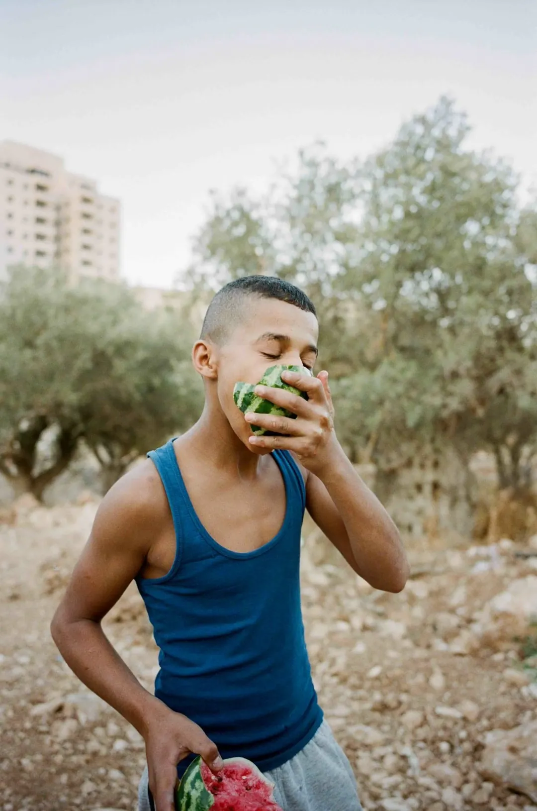 Un jeune homme mange une pastèque.